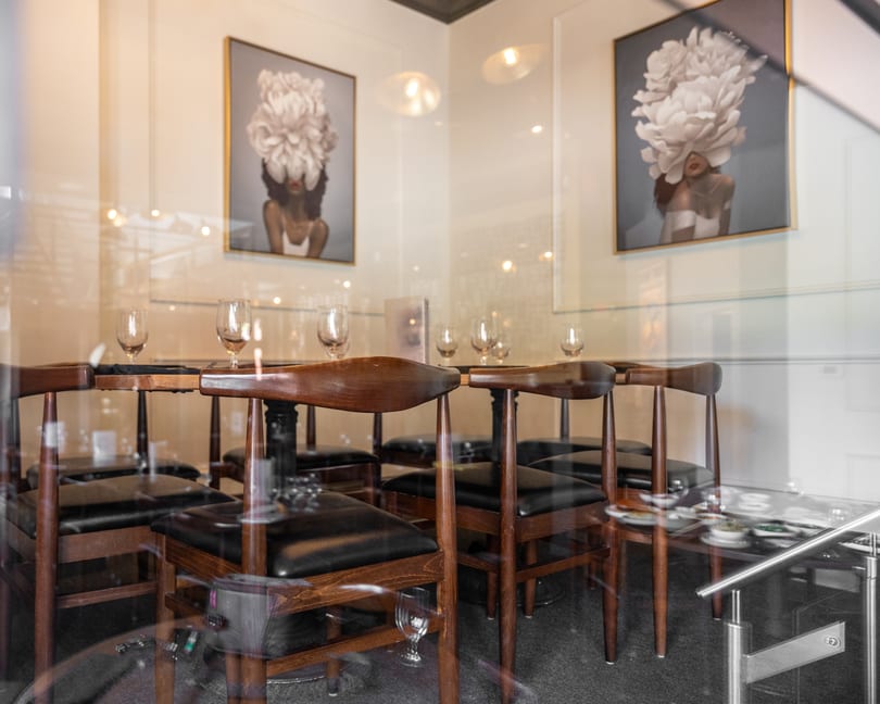 Elegant restaurant dining room with wooden tables, chairs, and distinctive floral artwork on the walls.