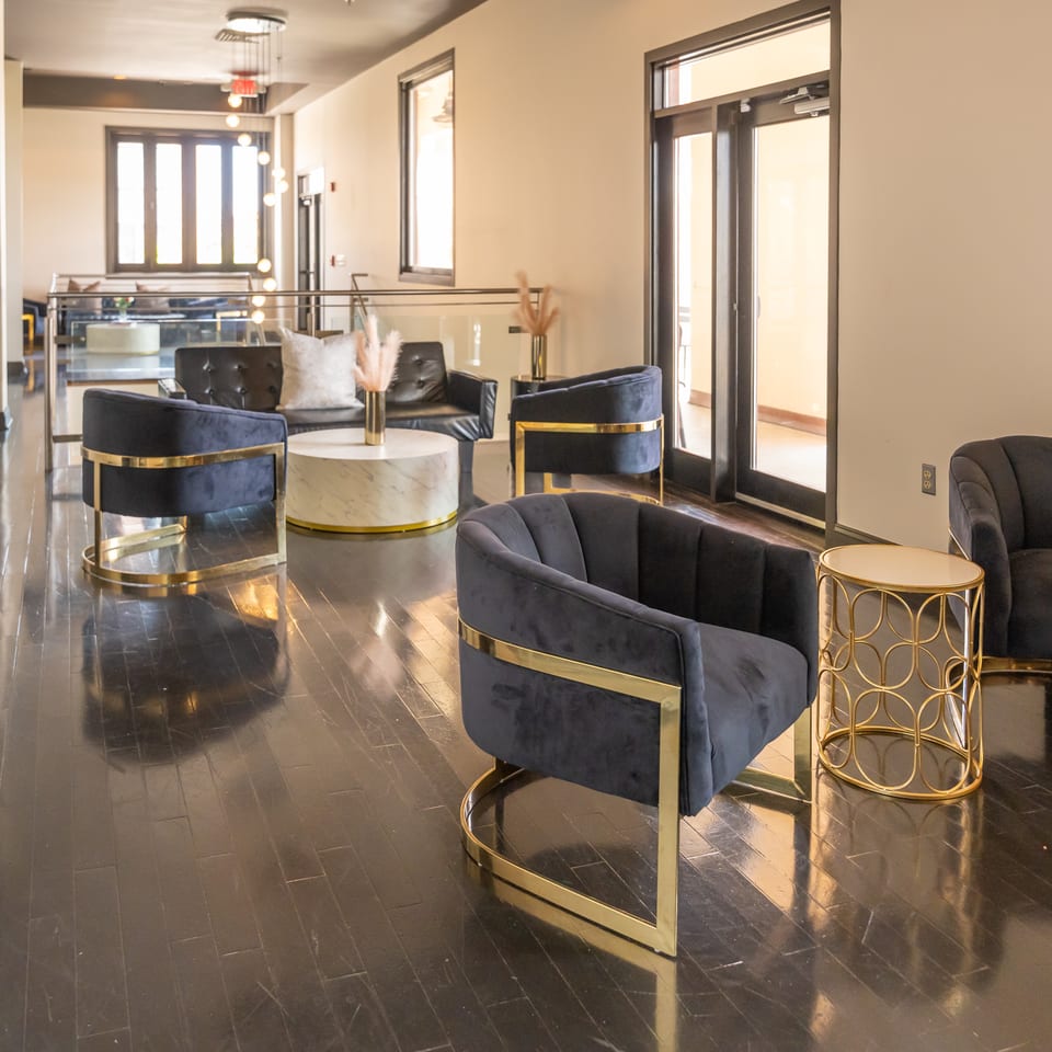 Elegant lounge area featuring dark velvet chairs with gold frames and a marble coffee table.