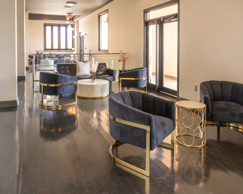 Elegant lounge area featuring dark velvet chairs with gold frames and a marble coffee table.