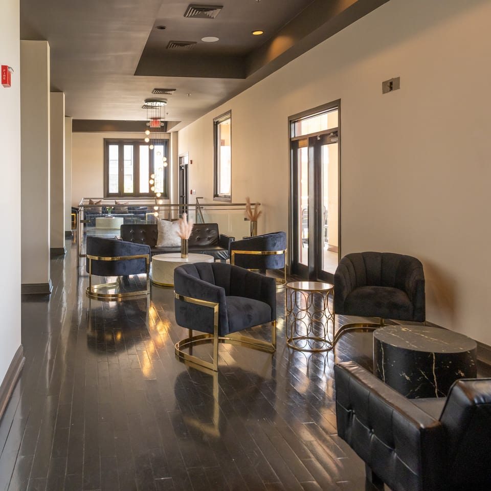 Stylish restaurant lounge with black velvet chairs, gold tables, and dark polished wooden floors.