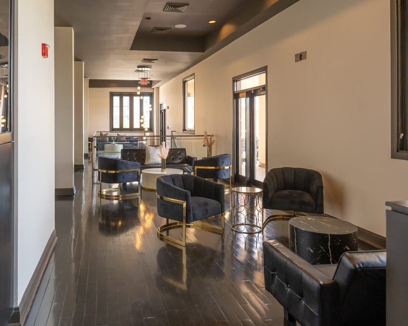 Stylish restaurant lounge with black and gold armchairs, marble tables, and dark wooden floors.