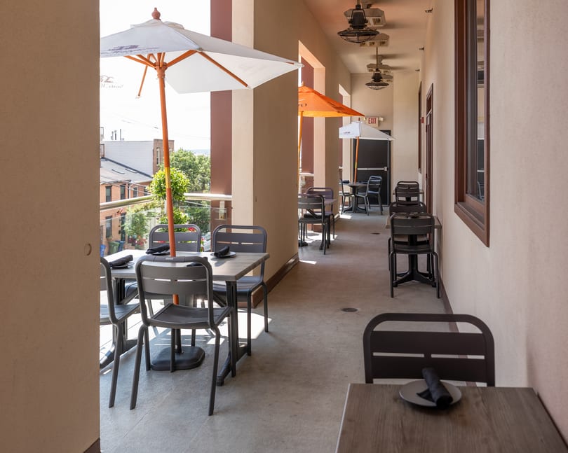 Restaurant's long outdoor patio with tables, chairs, umbrellas, and a scenic view of the town.
