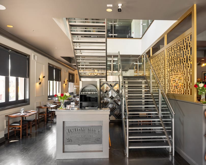 Union Hill restaurant's modern interior features a reception desk, staircase, dining area, and wine display.